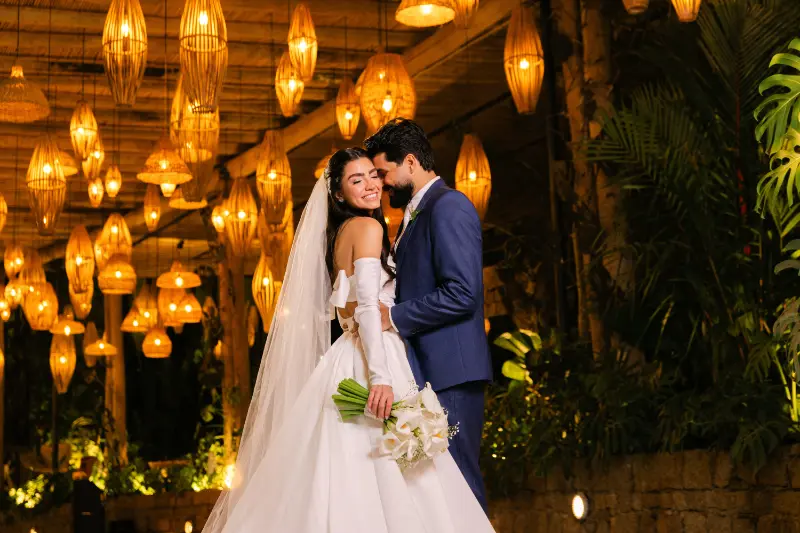 noivos abraçados embaixo de luzes em aárea externa