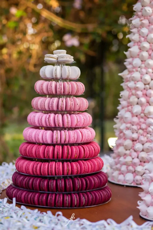 capa post: Torre de macarons em degradê rosa, do tom mais claro ao mais escuro, em mesa de doces ao ar livre.