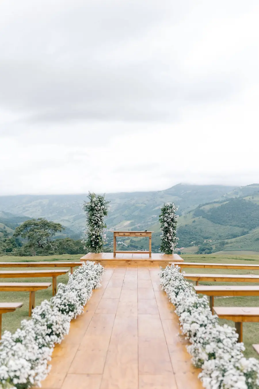 Altar em deck de madeira com vista para montanhas e flores brancas.