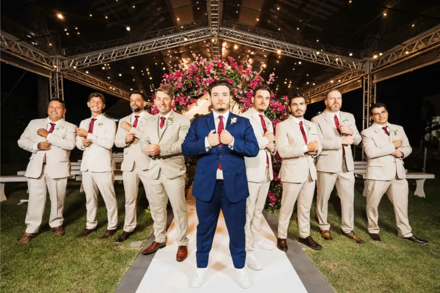 Noivo de terno azul e padrinhos de terno bege com gravata vinho