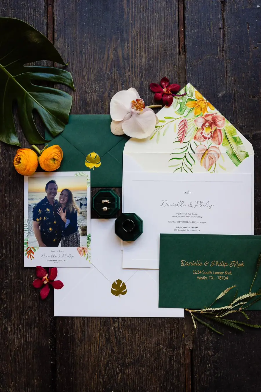 Kit de papelaria de casamento tropical com envelope verde e forro floral colorido, convite branco e foto dos noivos.