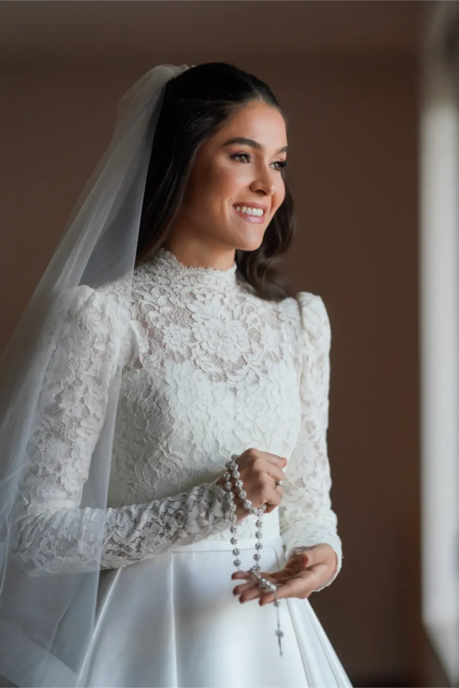 Noiva sorridente segurando terço simples prateado.