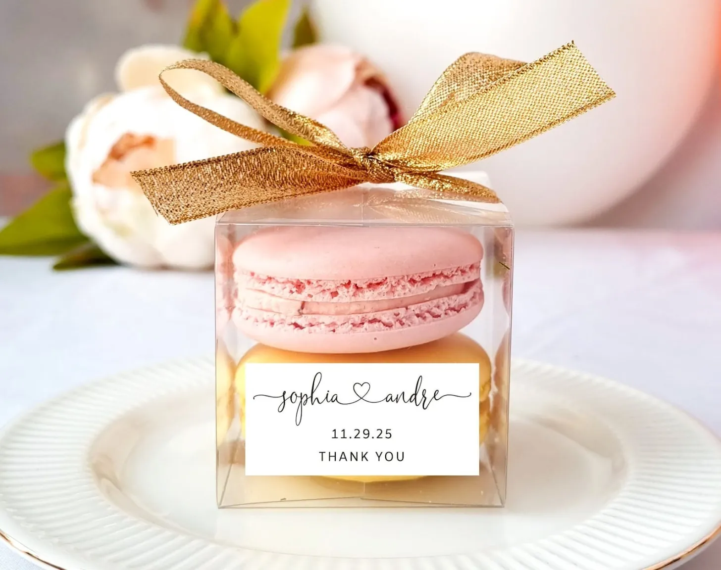 Caixa transparente com macarons rosa e amarelo, lembrancinha de casamento personalizada com tag dos noivos e laço dourado.