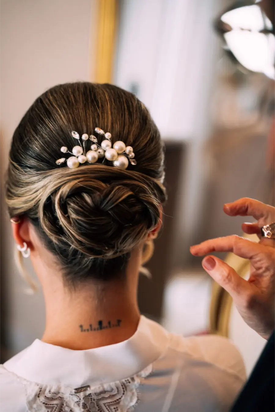 Coque baixo trançado com acessório de pérolas no cabelo de noiva.