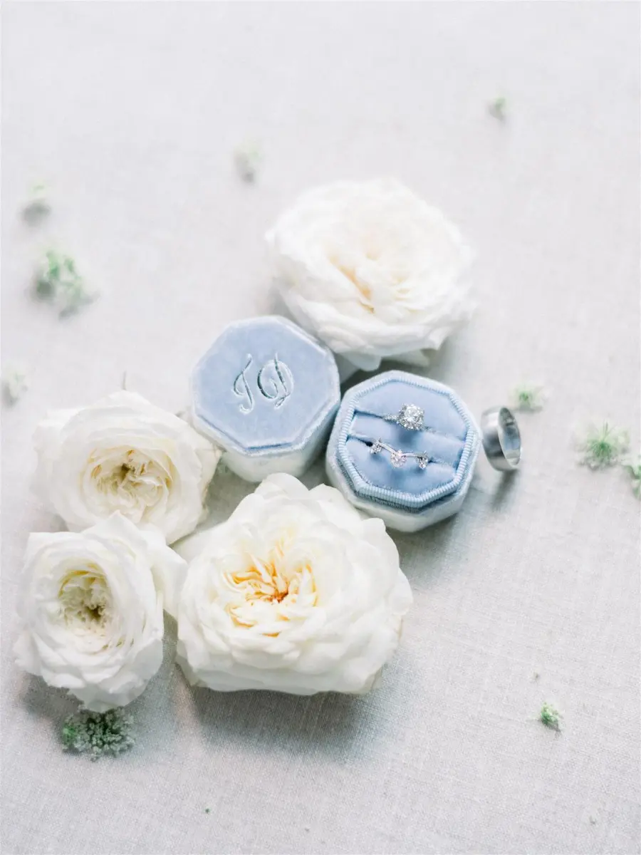 Caixa de veludo azul serenity com anel de noivado e flores brancas