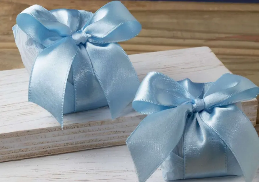 Tradicional lembrancinha de casamento embalada em papel branco com la&ccedil;o de fita azul.