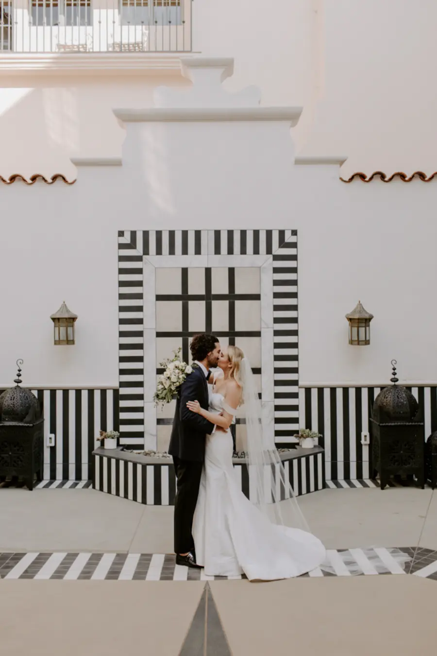 Noivos se beijando em altar moderno com listras pretas e brancas durante cerim&ocirc;nia de casamento ao ar livre