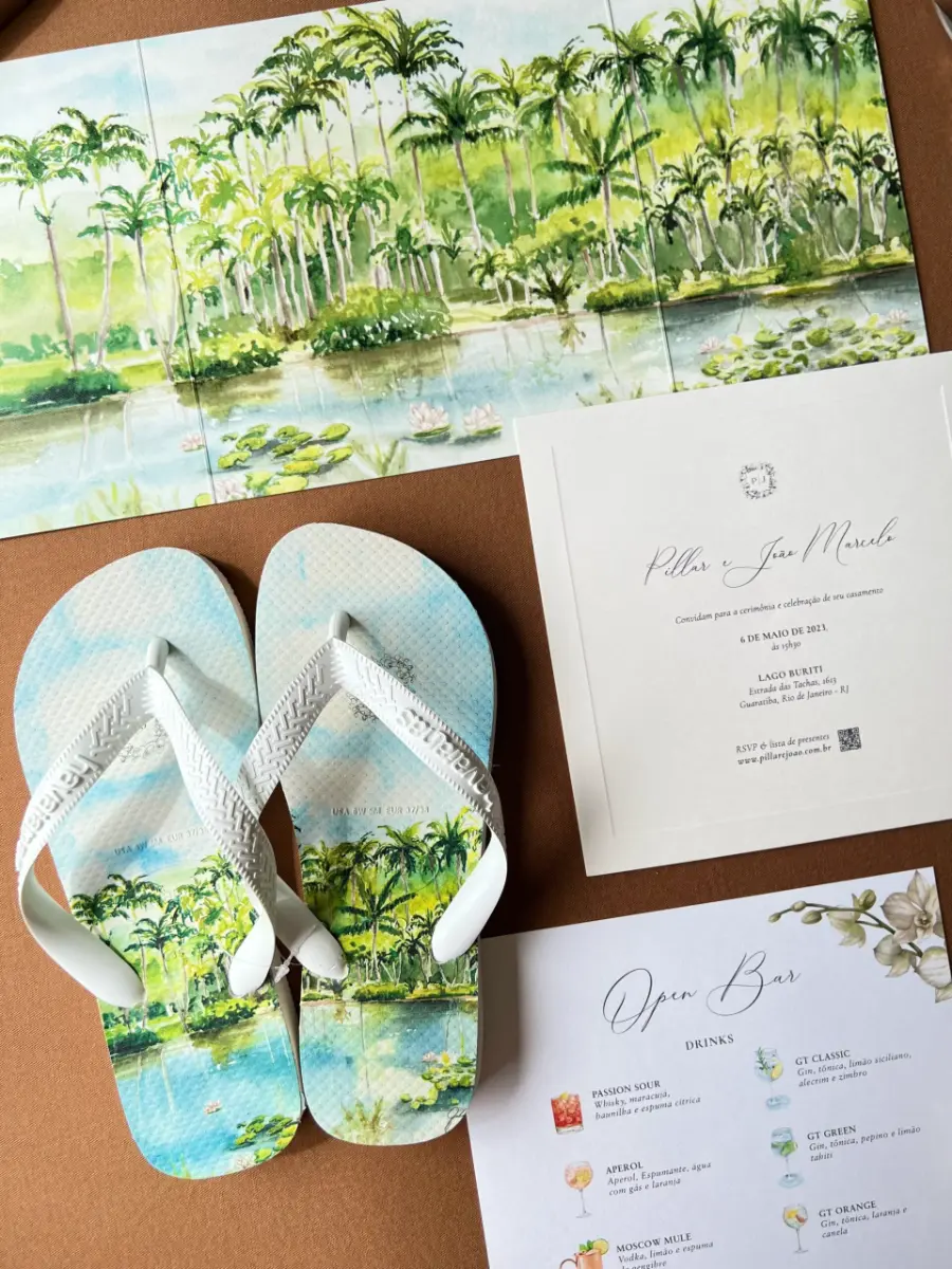 Convite de casamento acompanhado de chinelos personalizados com estampa de palmeiras e lago, em aquarela verde e azul.
