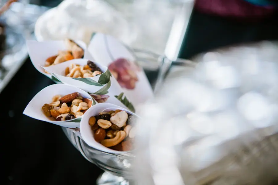 Cones de papel kraft servindo mix de castanhas e petiscos como aperitivo de casamento