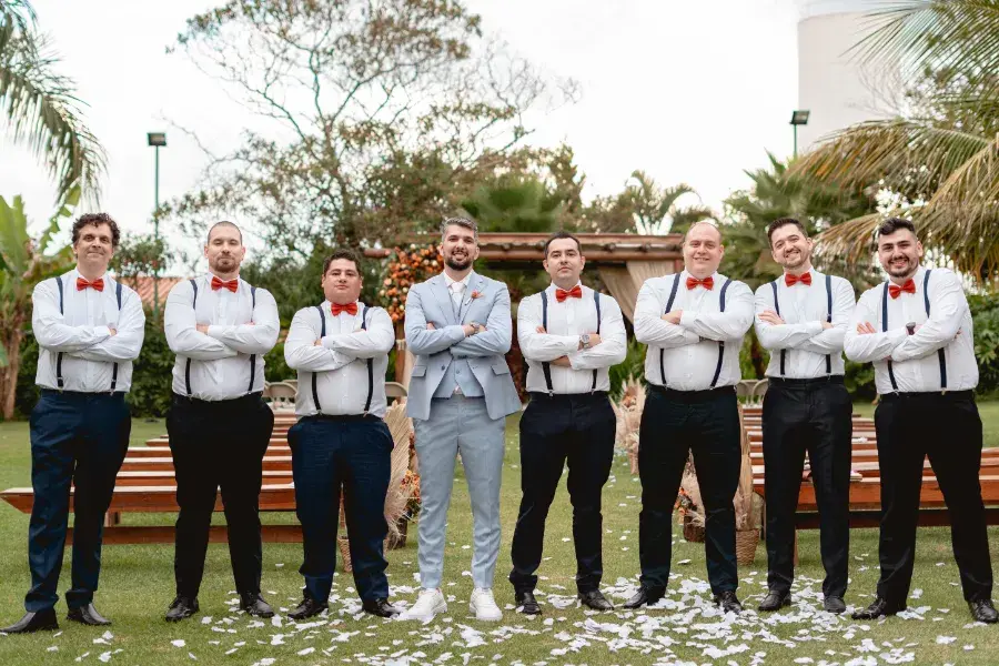 Noivo de terno azul claro e padrinhos com suspens&oacute;rios e gravata borboleta vermelha