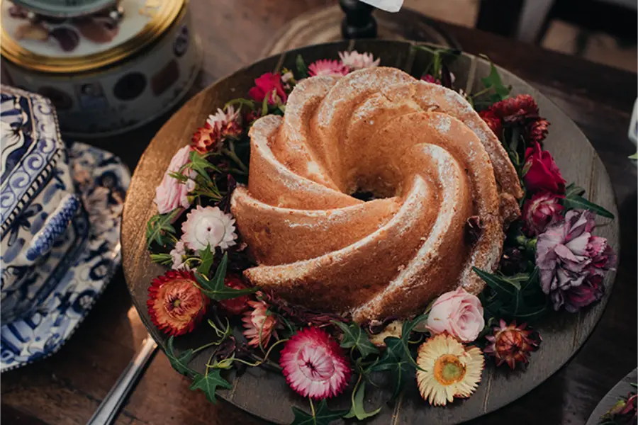 Bolo caseiro simples em formato redondo decorado com flores naturais em casamento ao ar livre.