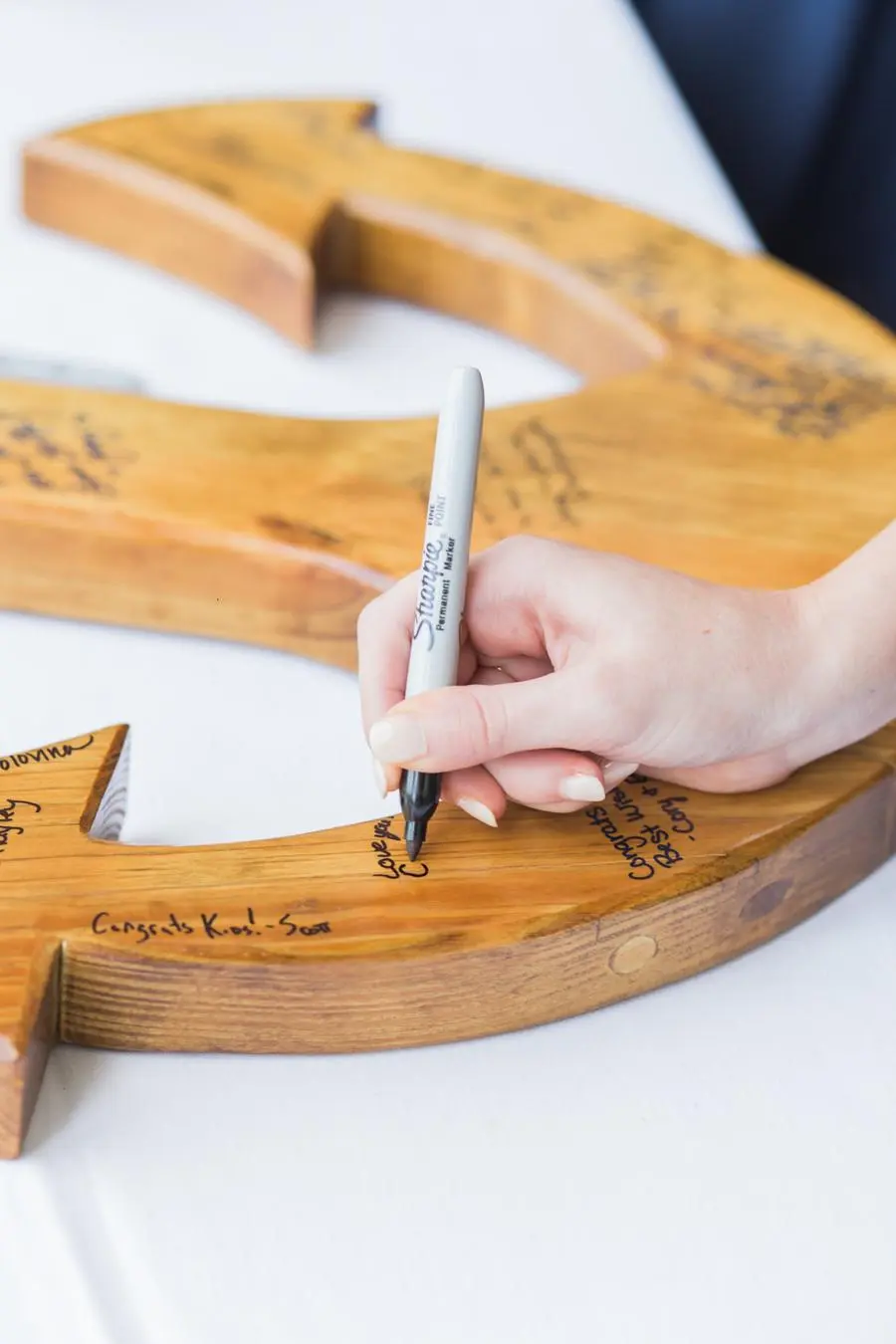 M&atilde;o escreve mensagem com caneta em &acirc;ncora de madeira usada como livro de assinaturas em casamento militar.
