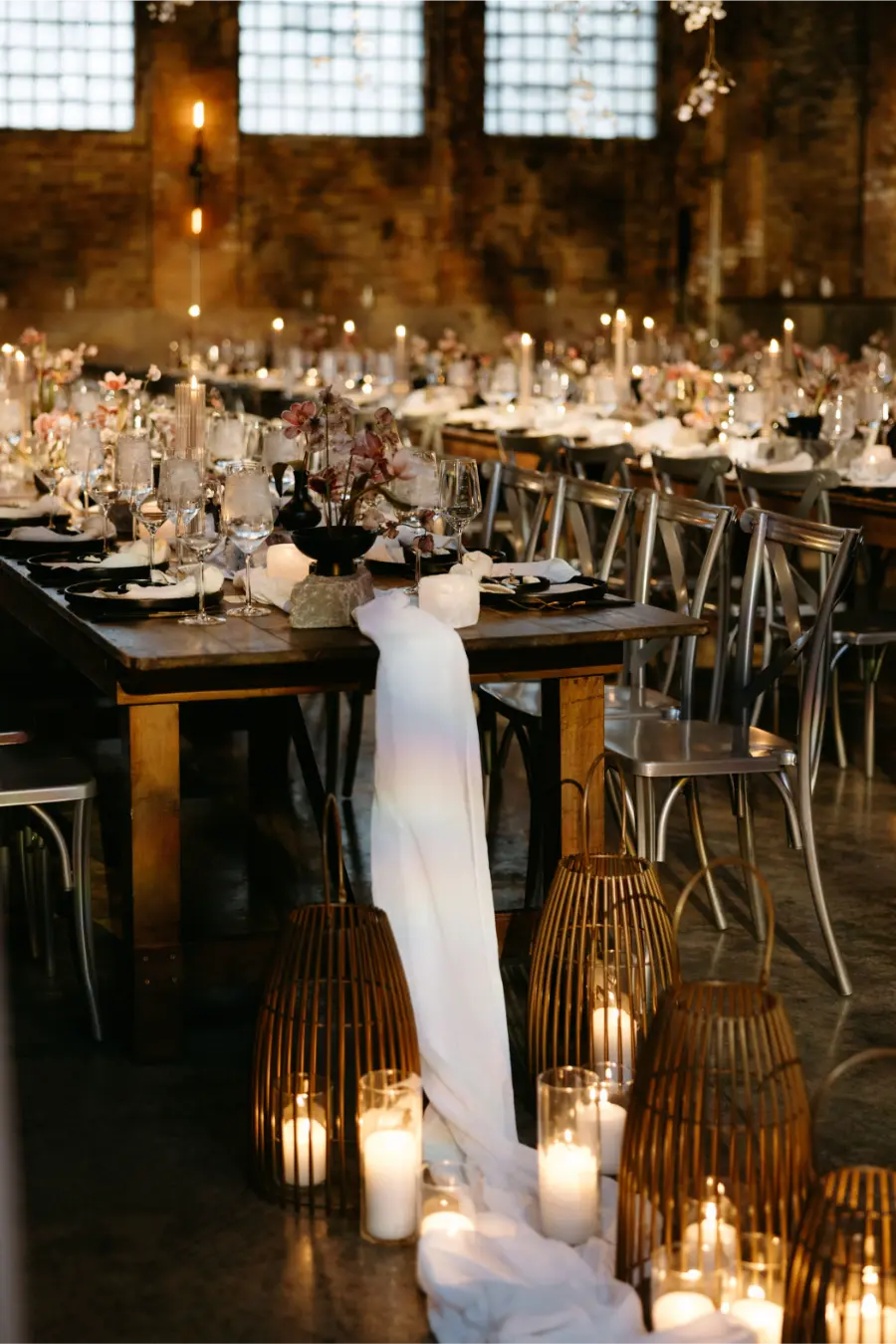 Decora&ccedil;&atilde;o de casamento em estilo industrial com mesas de madeira, velas e detalhes preto e branco.