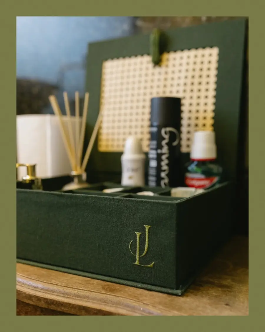 Kit toilette de casamento em caixa verde personalizada com iniciais JL, contendo difusor, enxaguante bucal, spray e outros itens de cuidado pessoal.