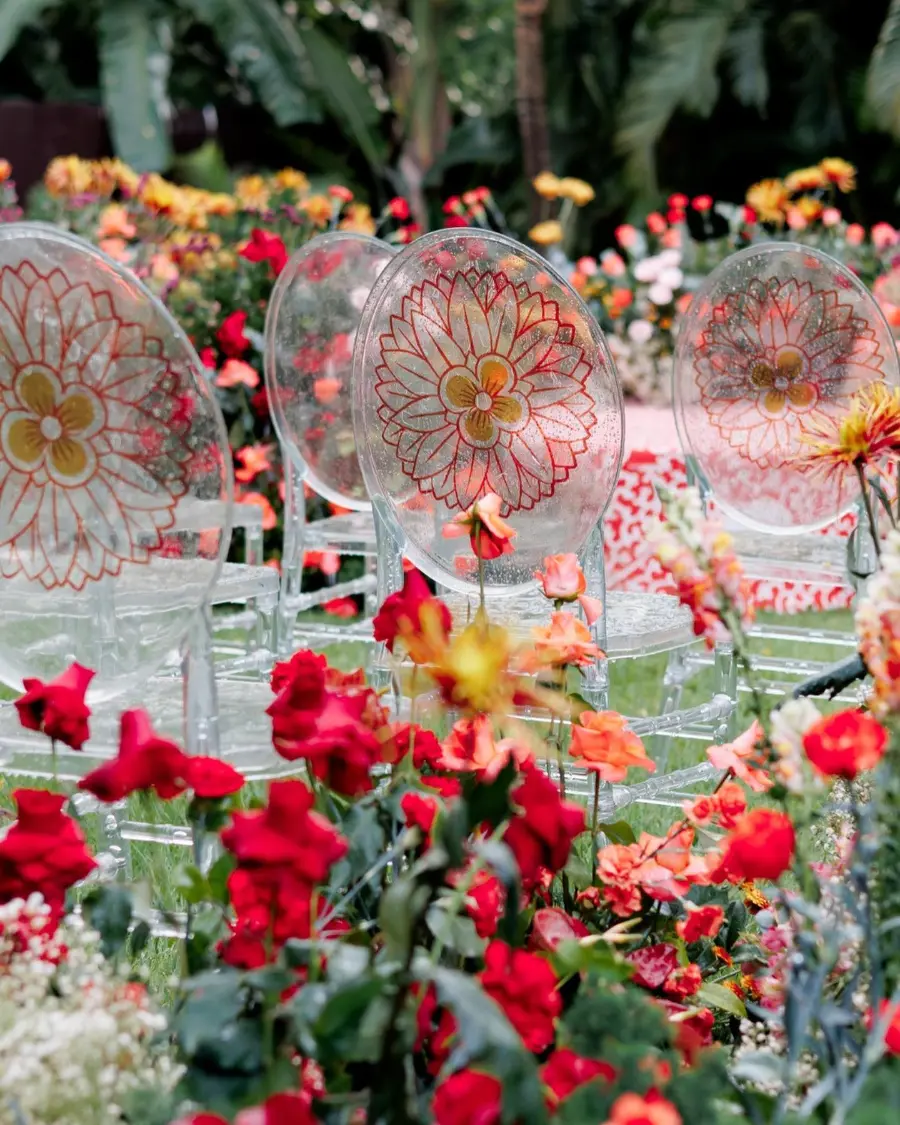 Cadeiras transparentes Ghost personalizadas com arte floral laranja em cerimônia ao ar livre com jardim florido