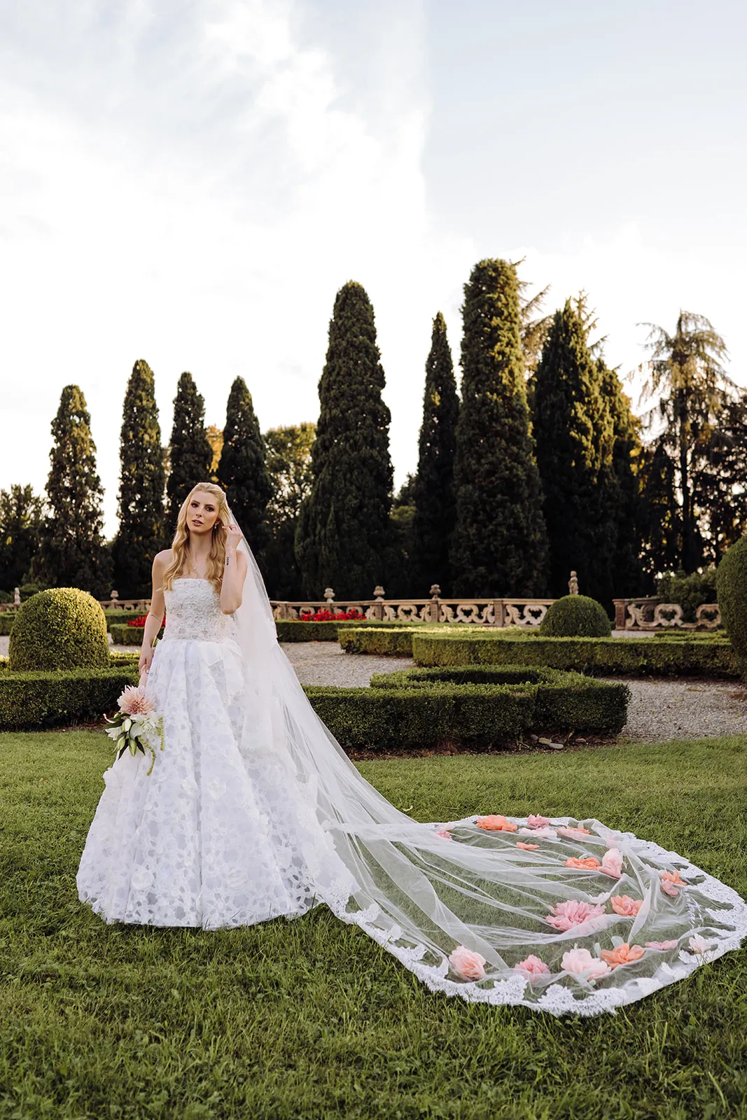 noiva com vestido elegante e véu longo nos jardins da italia