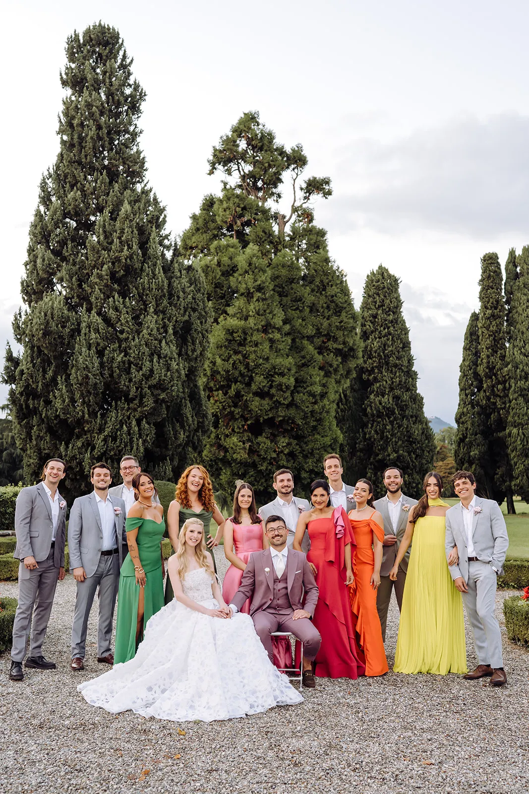 casal de noivos e convidados com tenros cinzas e madrinhas de vestidos coloridos em destination wedding italiano