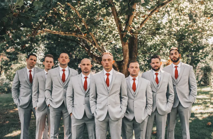 Grupo de padrinhos com ternos cinza claro e gravata vermelha lisa