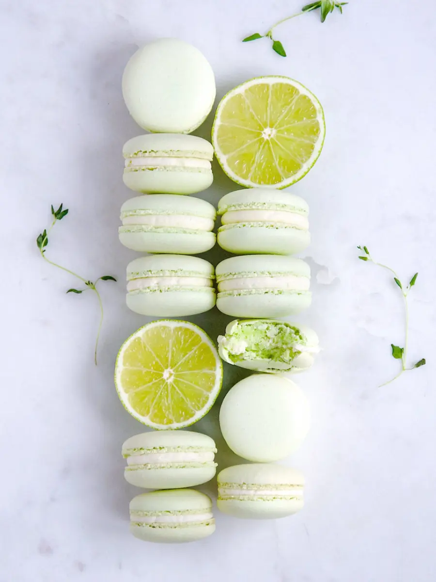 Macarons verdes com recheio claro, acompanhados por fatias de limão fresco.