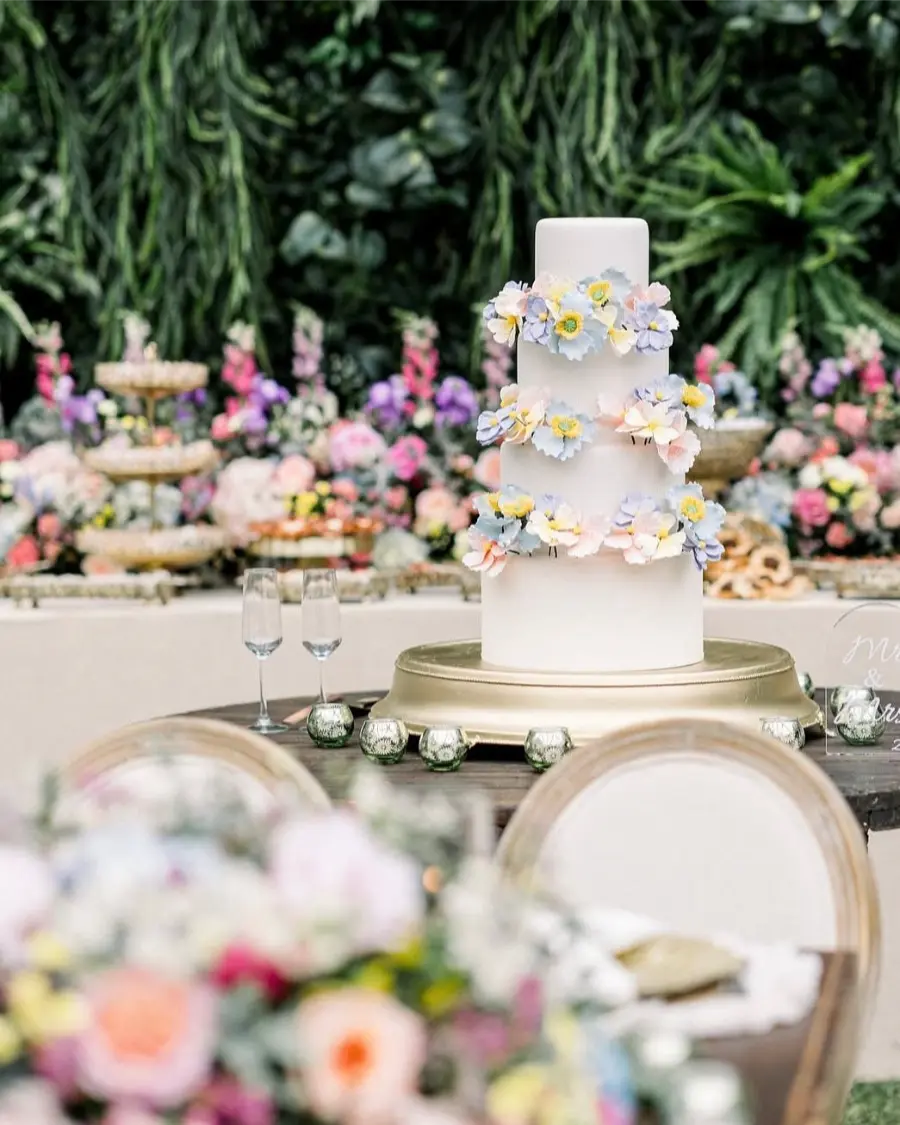 Bolo fake de três andares com flores coloridas em jardim externo decorado com arranjos florais