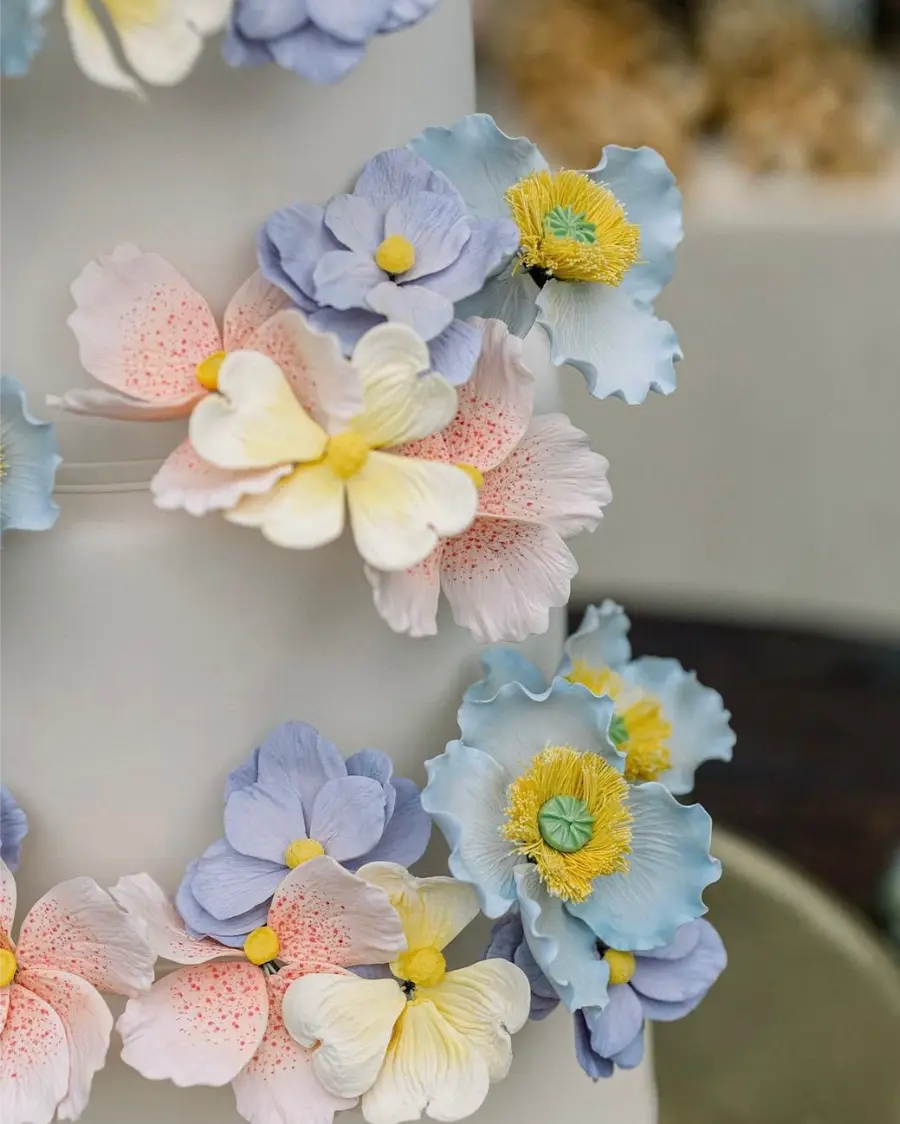 Detalhe de flores coloridas em tons de azul, rosa e amarelo decorando bolo fake de casamento