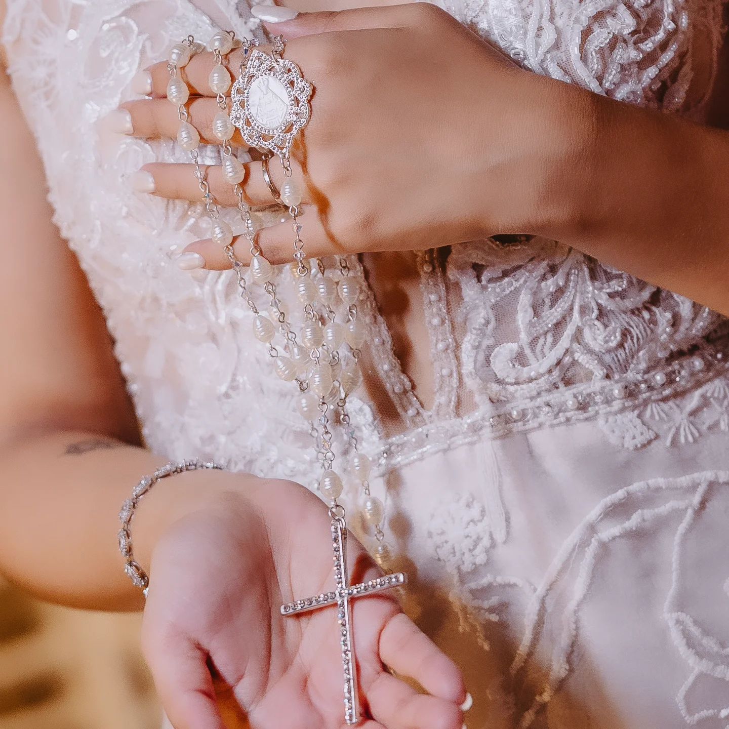 Close da noiva segurando terço de pérolas com crucifixo prateado.