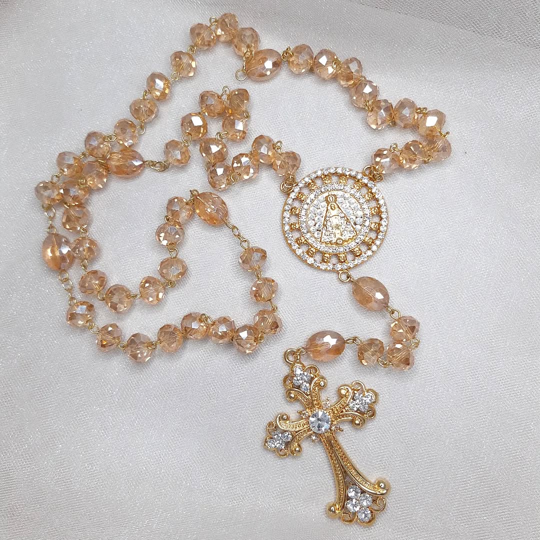 Terço dourado com contas em cristal âmbar e medalha central detalhada.