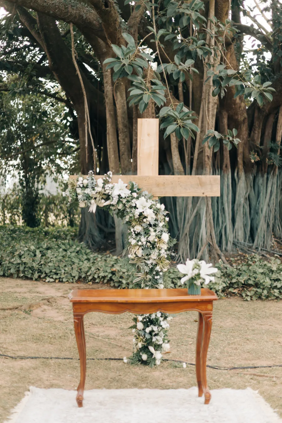 altar de casamento ao ar livre com cruz decorada com flores