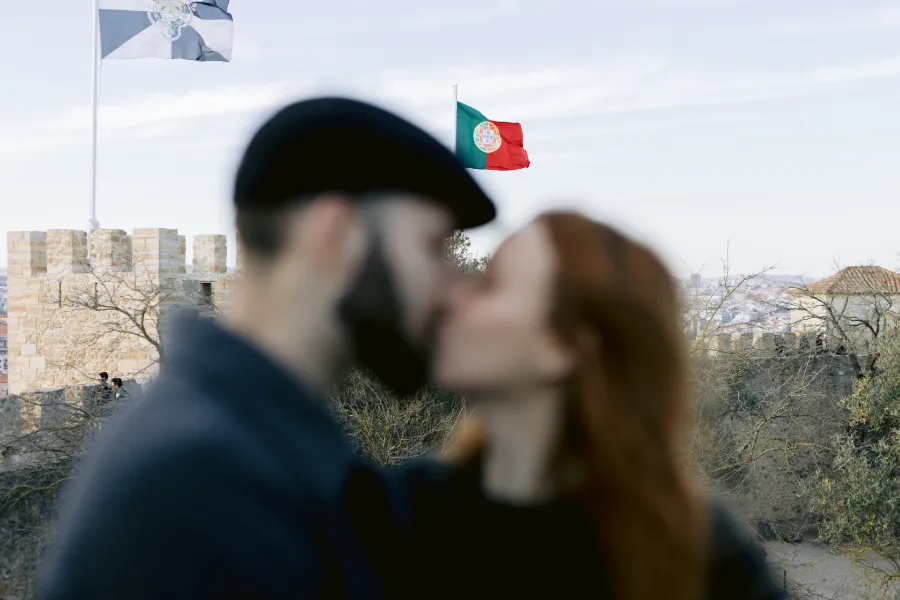 noivos se beijando e bandeira de portugal ao fundo