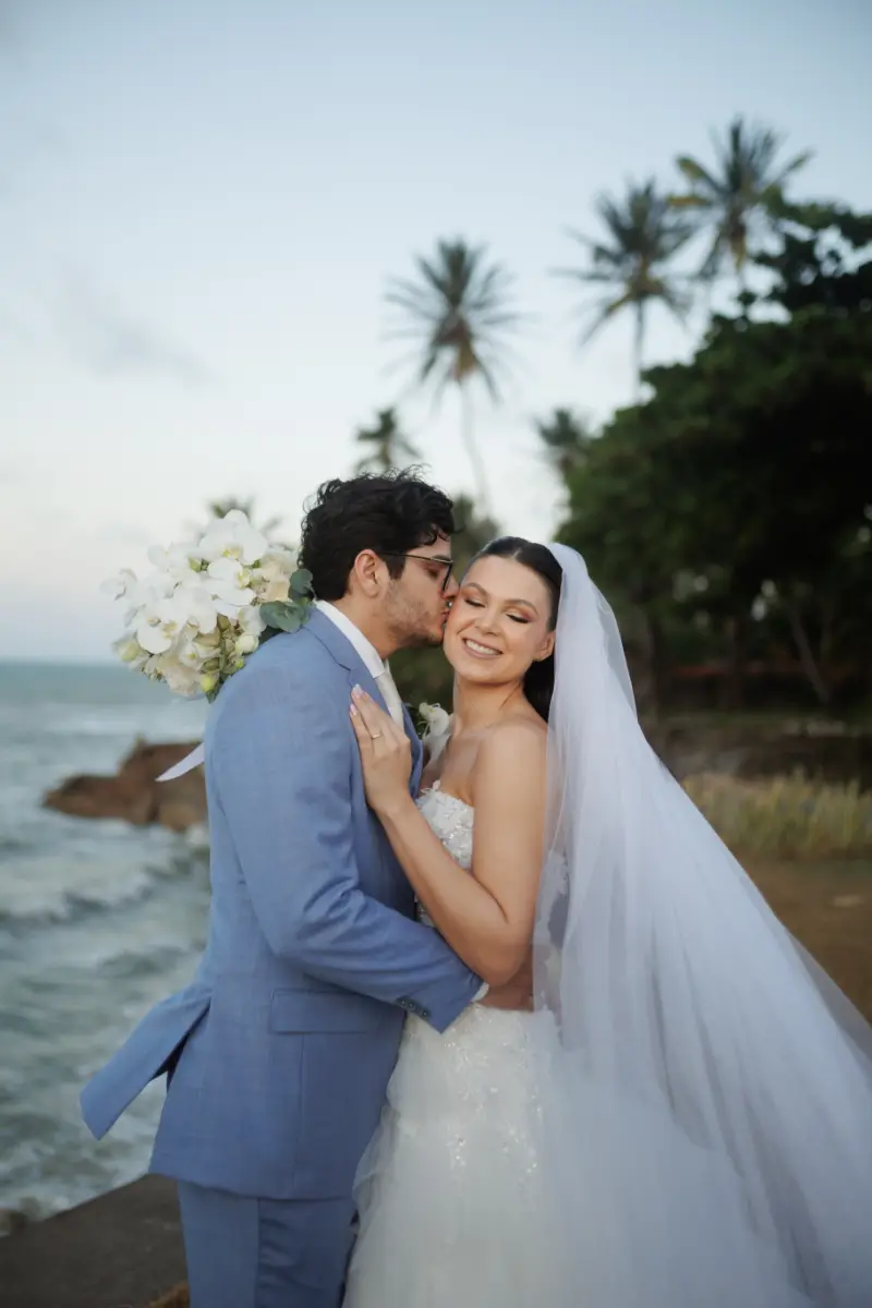 noivo beijando a bochecha da noiva na praia