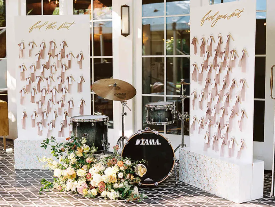 decoração de casamento com bateria musical com flores e backdrop com marcação das mesas para os convidados