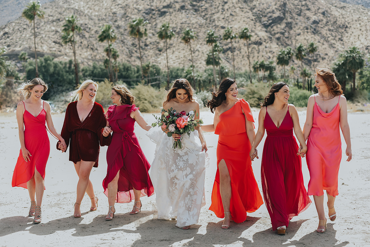 noiva ao lado de madrinhas de rosa, laranja e vermelho