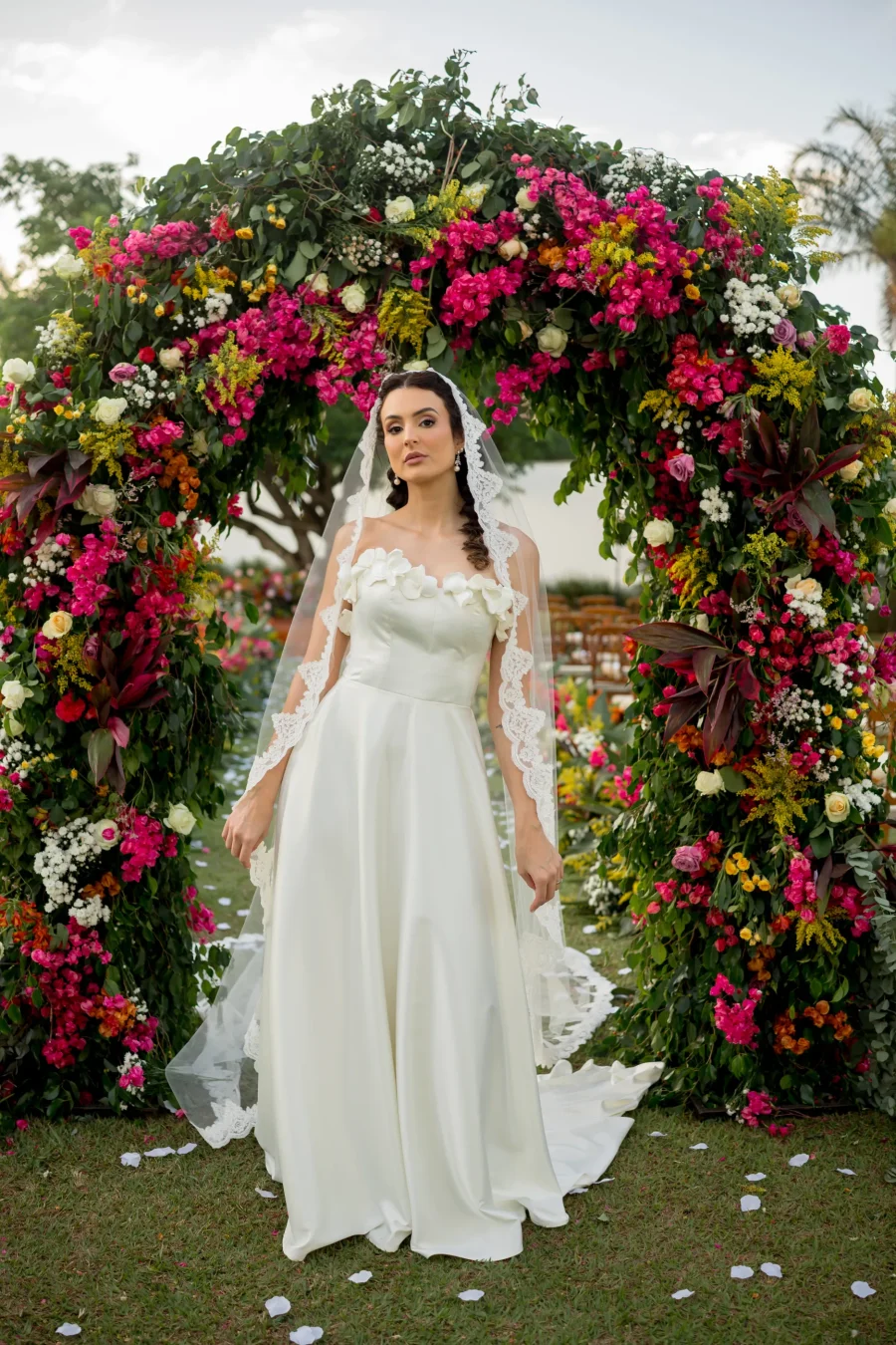 noiva com mantilha sob arco de flores