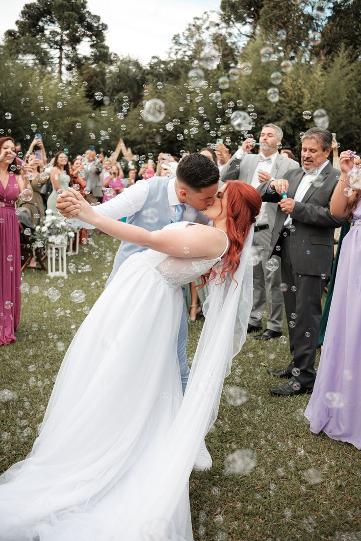 noivos se beijando no casamento no campo com saida com bolhas de sab&atilde;o