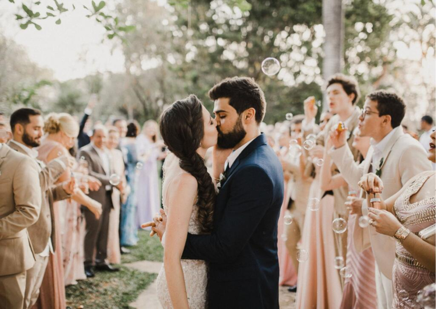 foto de casamento com sa&iacute;da dos noivos com beijo