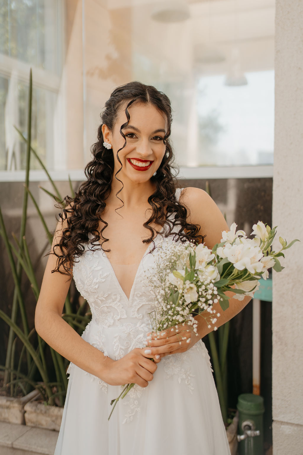 noiva com batom vermelho segurando buque de flores brancas