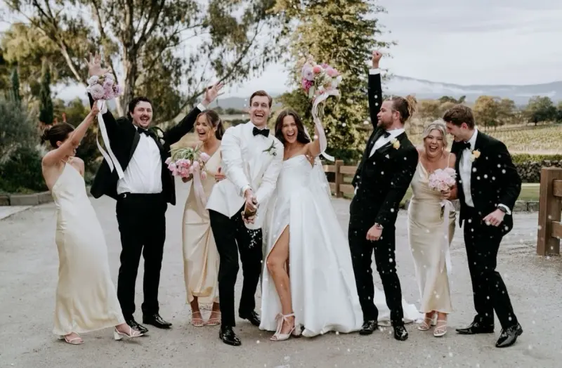 noivos e padrinhos comemorando o casamento estourando champagne