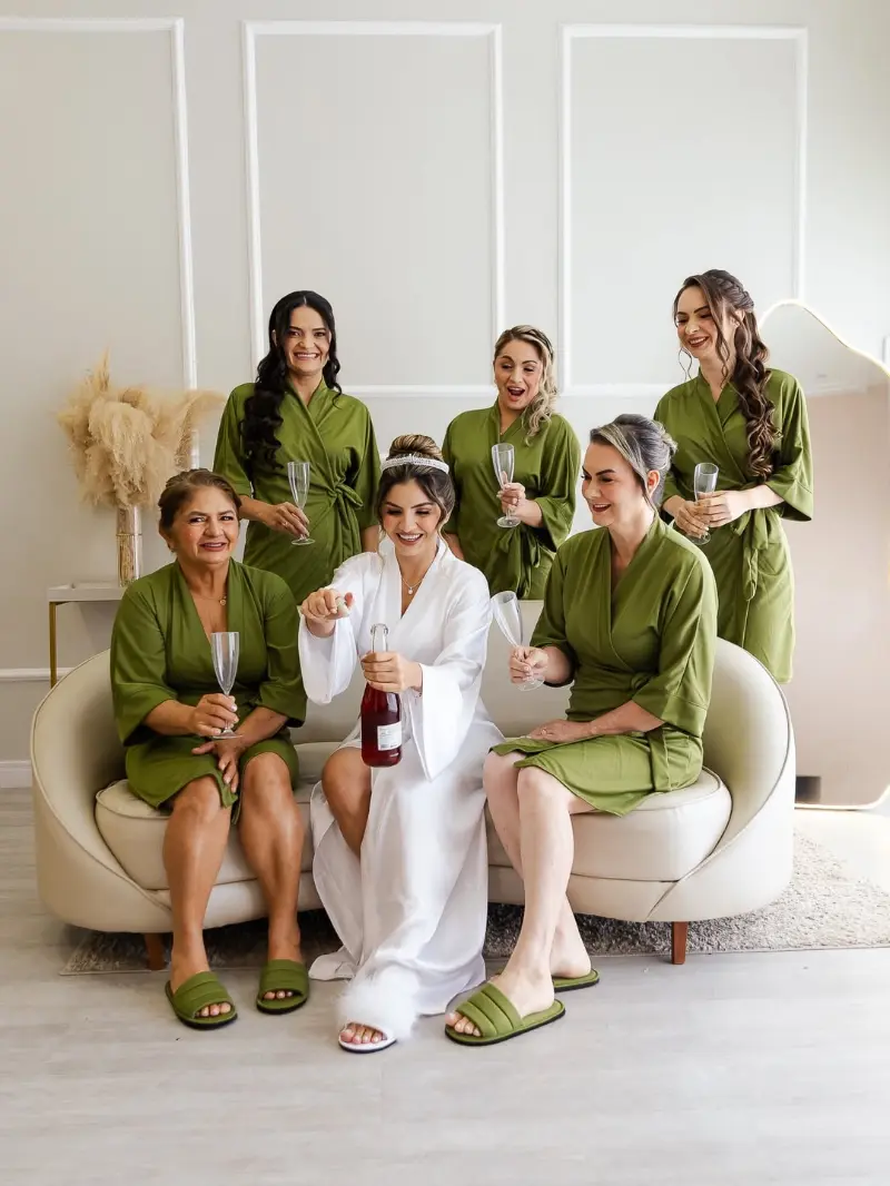 noiva com robe branco ao lado das madrinhas de robe verde