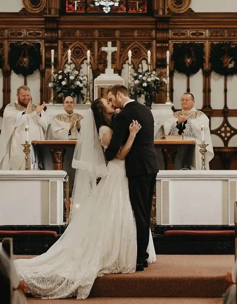 beijo dos noivos em casamento na igreja. noiva veste um vestido branco tradicional com v&eacute;u