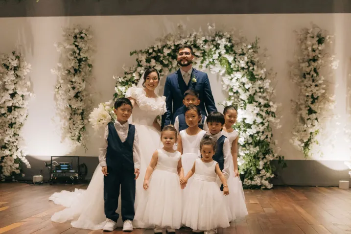 noivos ao lado de daminhas e pajens no salão