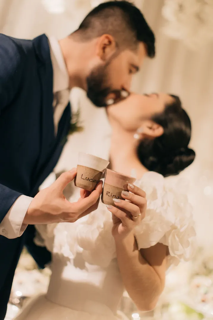 noivos se beijando enquanto brindam com copos de café