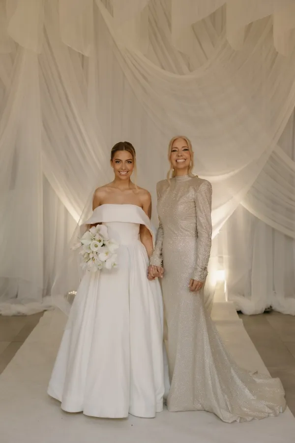 noiv aoa lado da m&atilde;e com vestido cinza e ao fundo tecido plissado