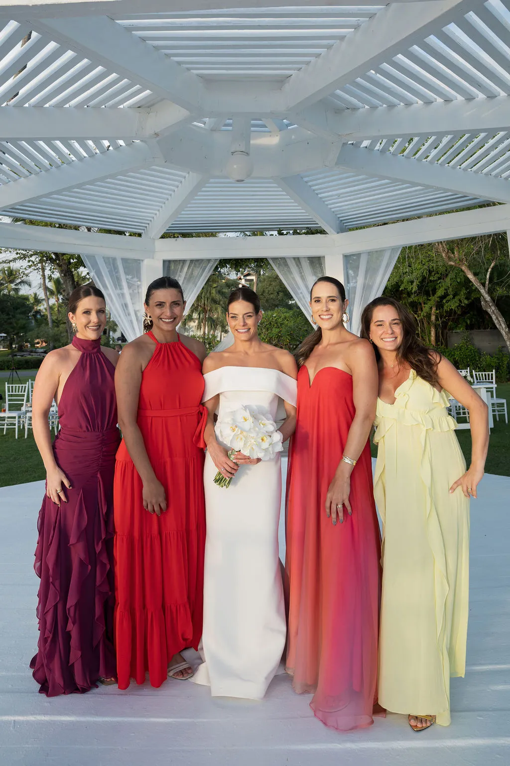noiva ao lado das madrinhas de casamento de vermelho rosa e amarelo