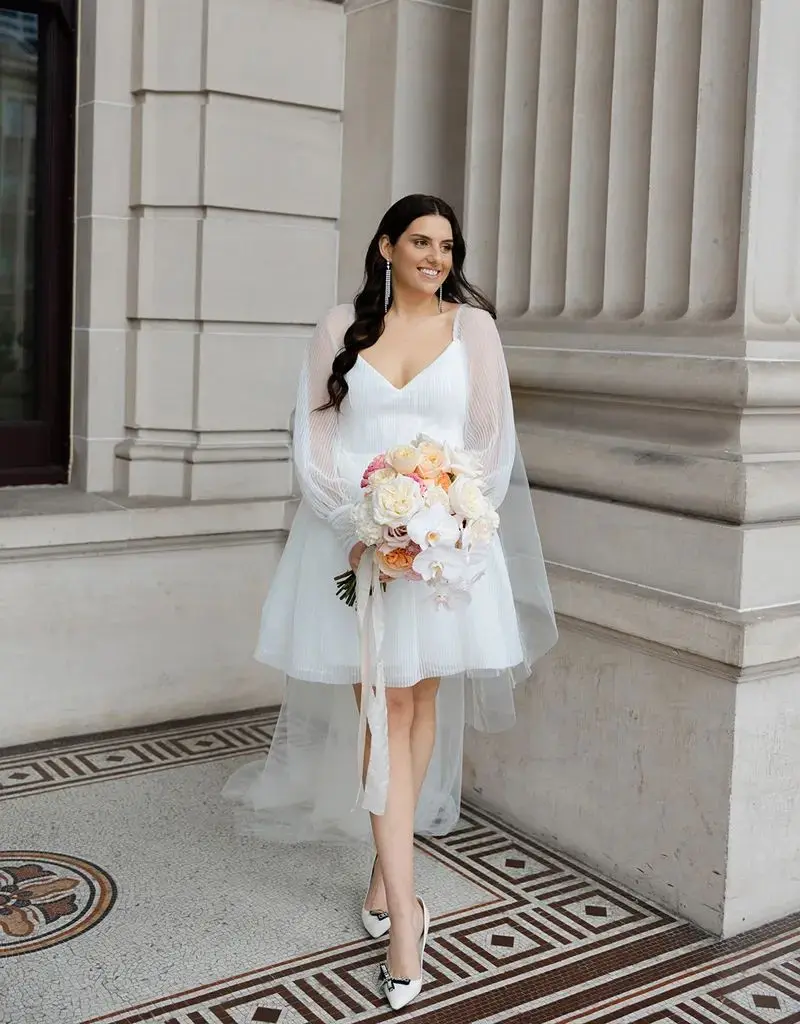 noiva com vestido midi segurando buque pequeno para casamento civil