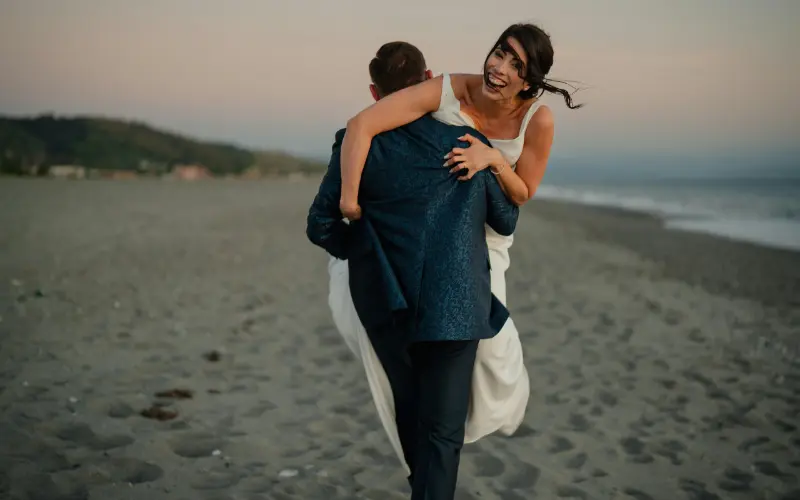 noiva sendo carregada pelo noivo na praia