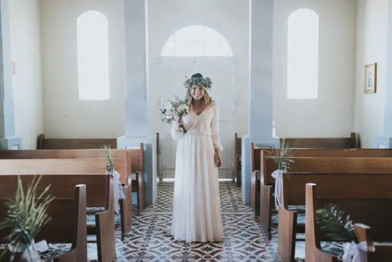 vestido de noiva na igreja cat&oacute;lica longo com tecido leve. A noiva est&aacute; usando coroa de folhas secas