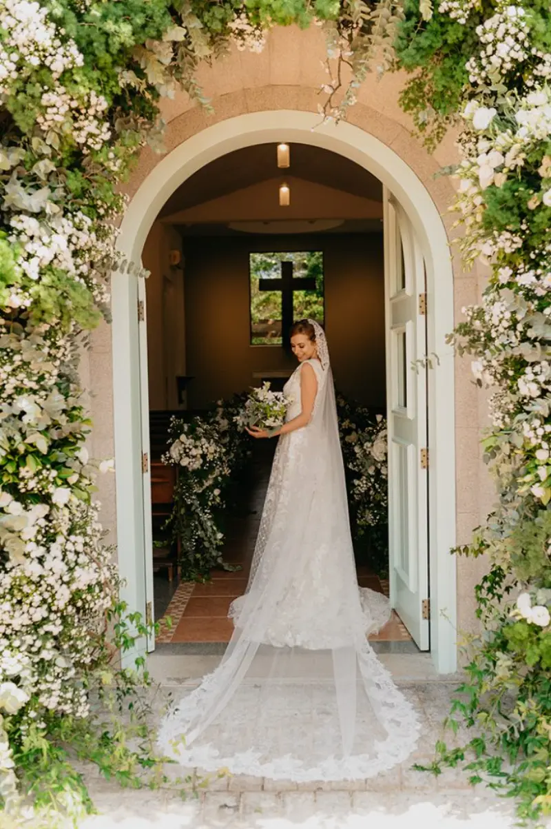 noiva na entrada da capela com vestido longo rendado e mantilha