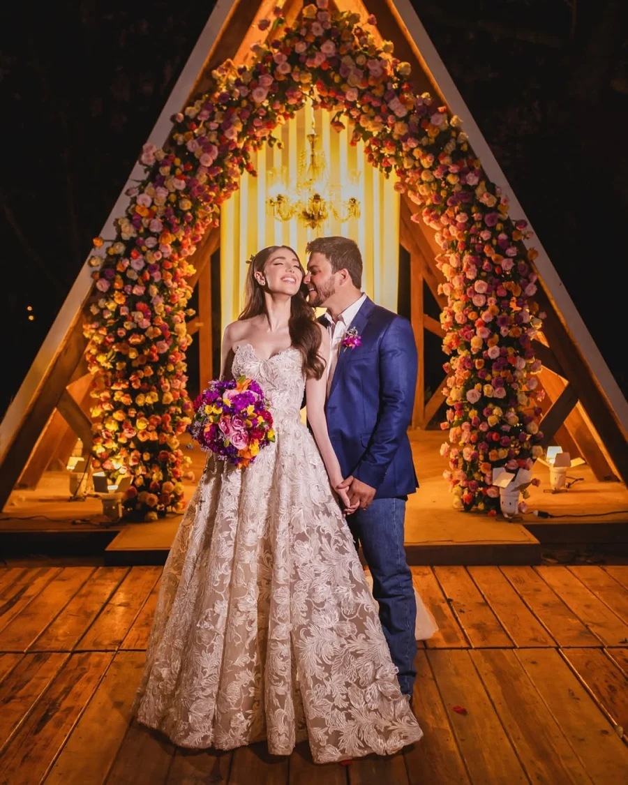 noiva com vestido tomara que caia rendado ao lado do noivo de terno azul