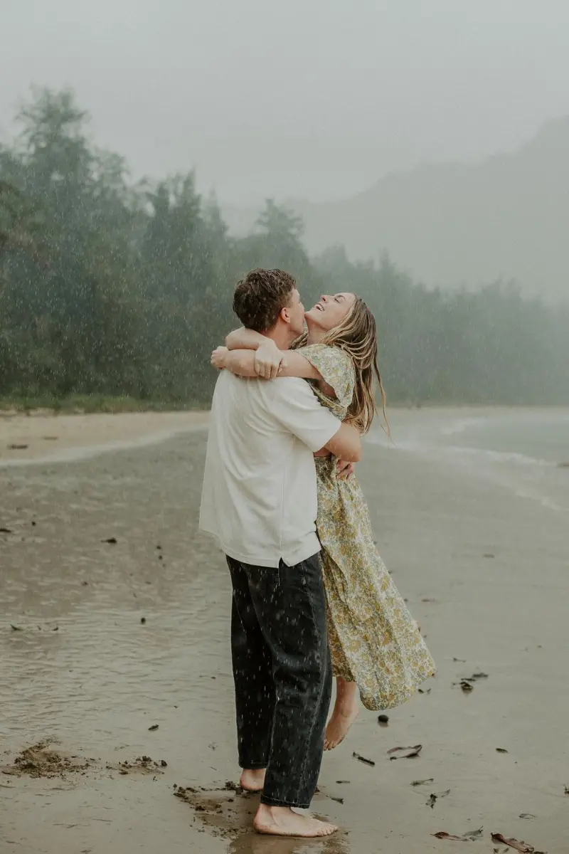 casal abraçado na praia sob chuva