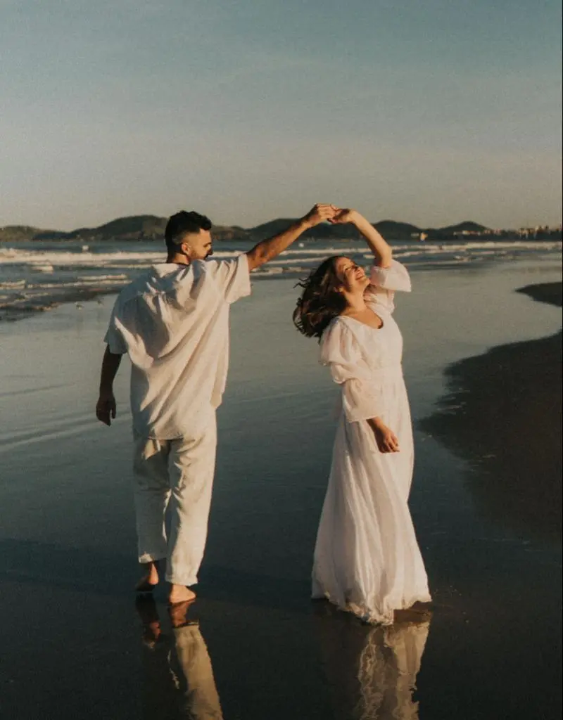 casal dançando na beira da praia durante o pôr do sol